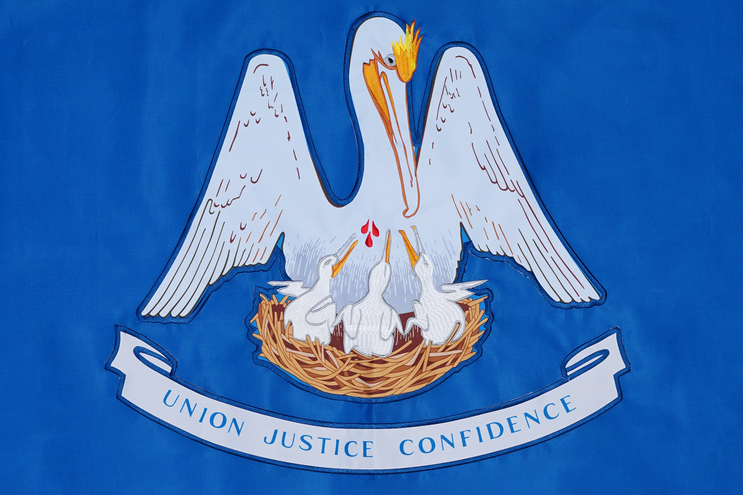 The Louisiana State Flag by Flag Stars Inc features a white pelican feeding three chicks in a nest on blue, with Union Justice Confidence on a ribbon below. 100% made in the USA.