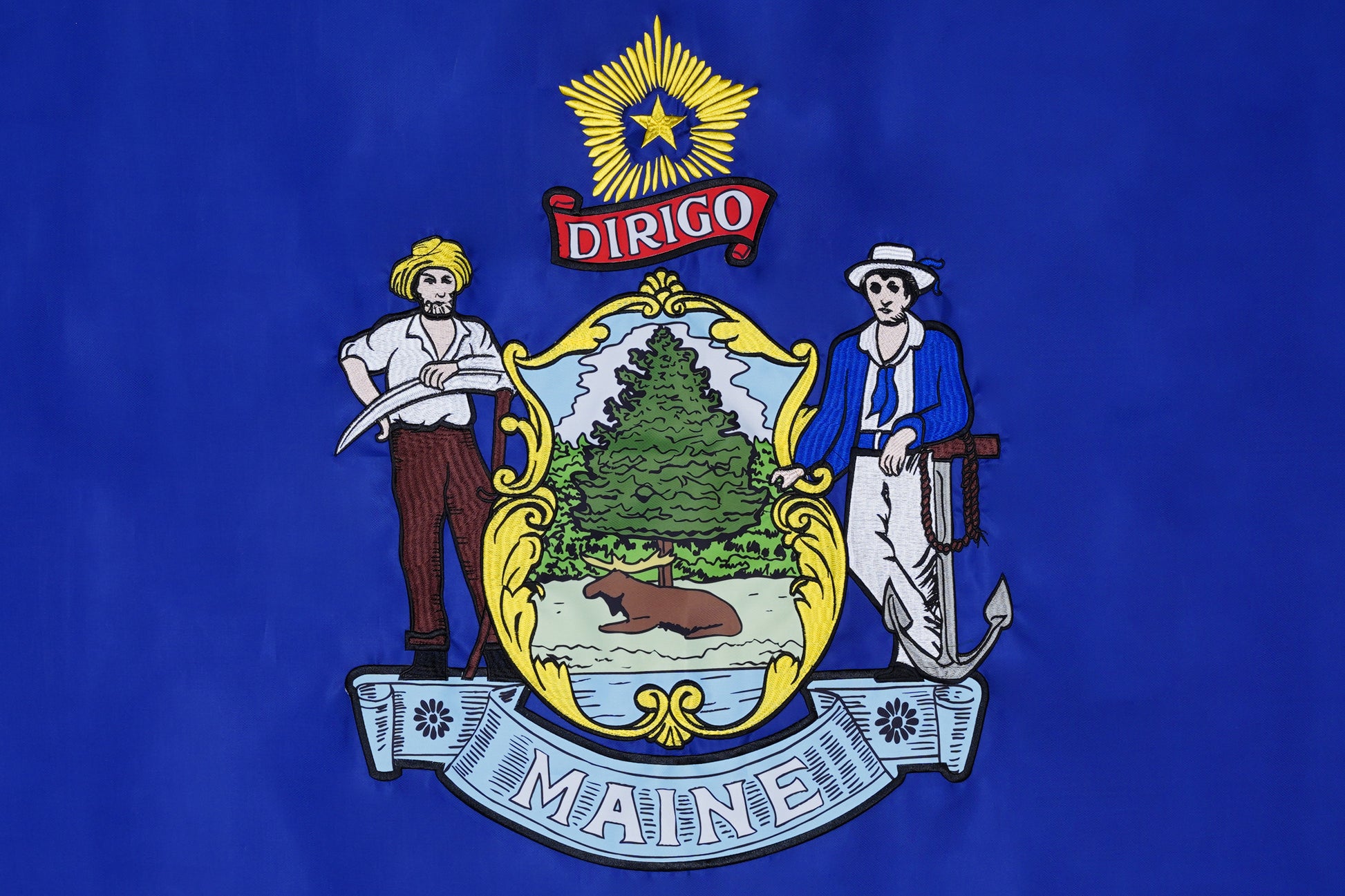 Flag Stars Inc Maine State Flag – 100% Made in USA. Features state coat of arms with pine tree, moose, farmer, sailor, and "Dirigo" star on blue. Raised embroidery offers elegance; durable for outdoor use.