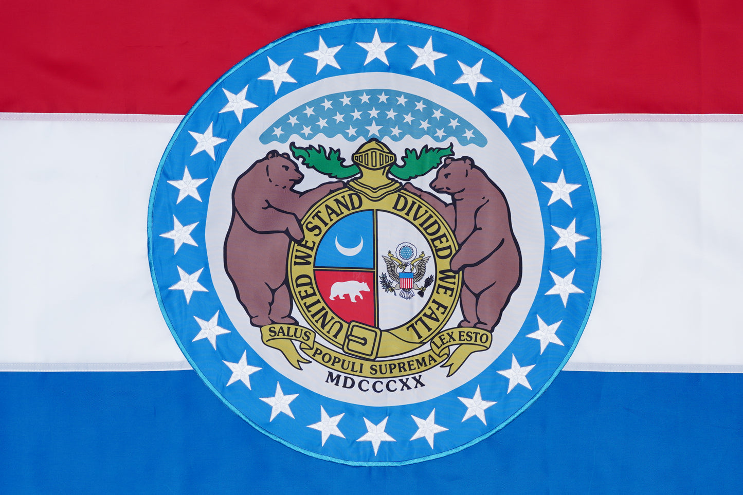 The Missouri State Flag - 100% Made in USA by Flag Stars Inc features red, white, and blue stripes, the state seal at the center flanked by two bears, all encircled by a ring of stars.