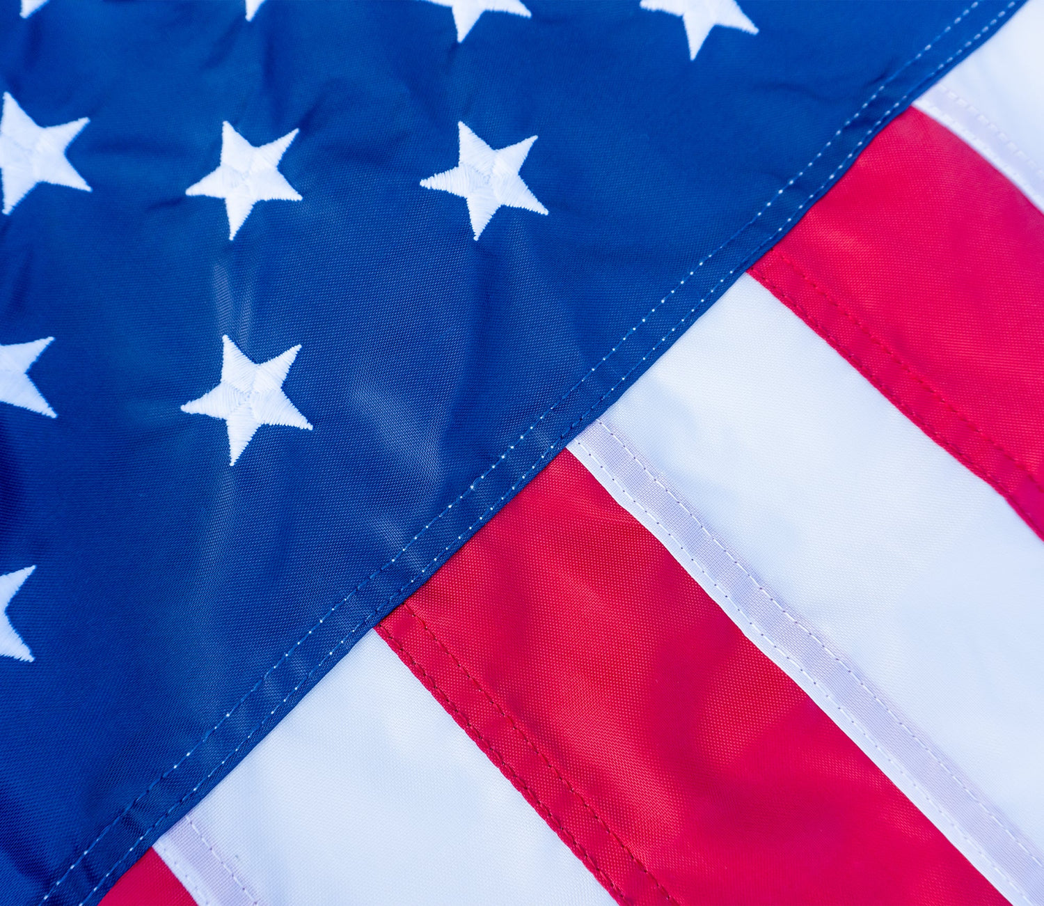 Close-up of a handmade American flag showing a section of blue with white stars, and red and white stripes. Crafted to be long lasting.
