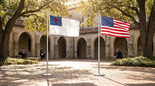 Outdoor christian flag with blue canton and red cross flying beside a U.S. flag on matching churchyard poles in morning light