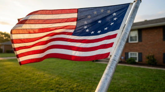 A 15-star fort mchenry flag flying on a residential flagpole in warm morning sunlight