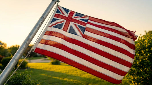 Grand union flag flying on a residential flagpole in afternoon sunlight for America's 250th celebration