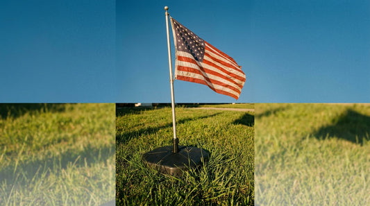 Freestanding no dig flagpole base on green grass flying an American flag in afternoon sunlight