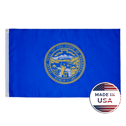 The Nebraska State Flag by Flag Stars Inc features the state seal in gold on blue with raised embroidery and a circular "Made in USA" label. 100% made in the USA and ideal for outdoor use.