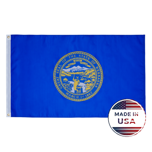 The Nebraska State Flag by Flag Stars Inc features the state seal in gold on blue with raised embroidery and a circular "Made in USA" label. 100% made in the USA and ideal for outdoor use.