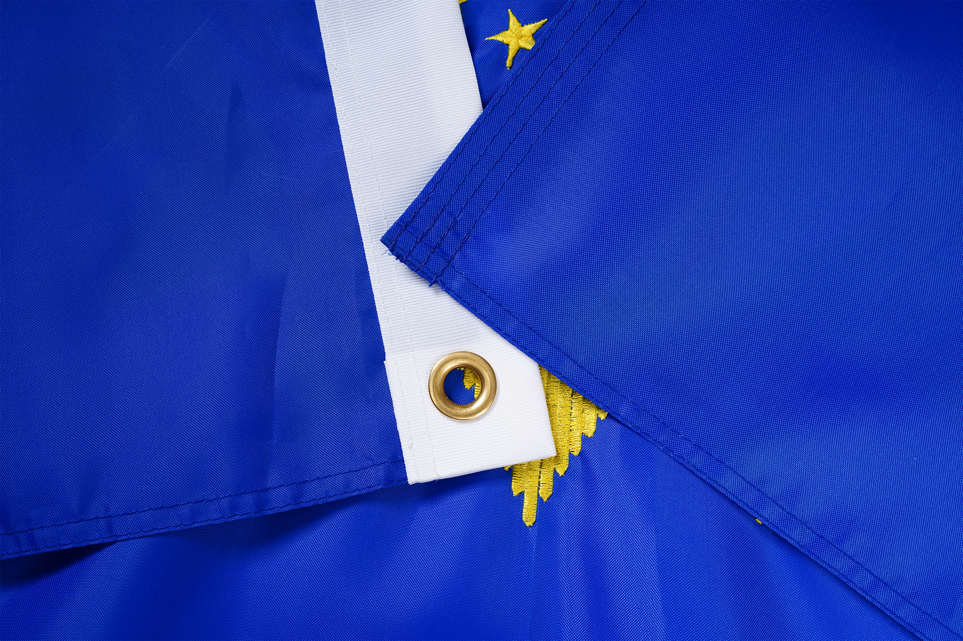Close-up of two North Dakota State Flags by Flag Stars Inc, featuring gold grommets, yellow stars, and raised embroidery. Crafted for outdoor use and 100% made in the USA.