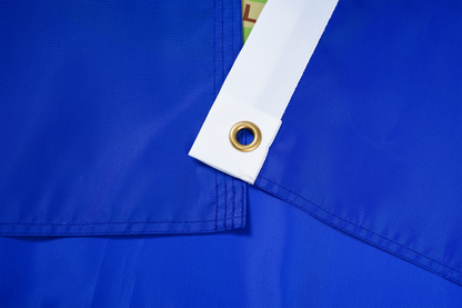 Close-up of the Montana State Flag by Flag Stars Inc, featuring overlapping blue fabric, a reinforced white edge, and metal grommet—100% made in the USA for outdoor use.